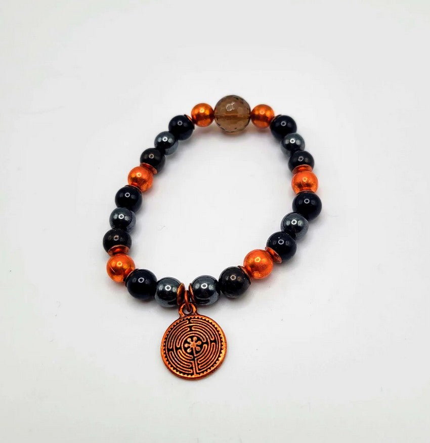 Beaded spiritual bracelet with black, silver, and copper beads, featuring a round labyrinth charm