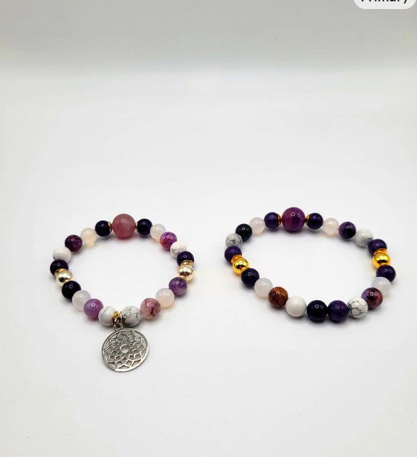 Two beaded gemstone bracelets with gold accents and one silver charm on white background