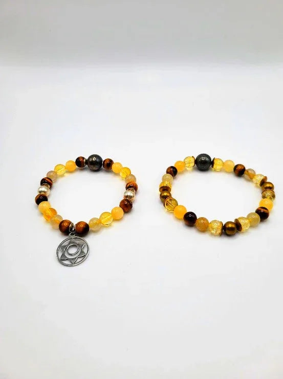 Yellow and brown beaded spiritual bracelets, one with a silver charm, on white background