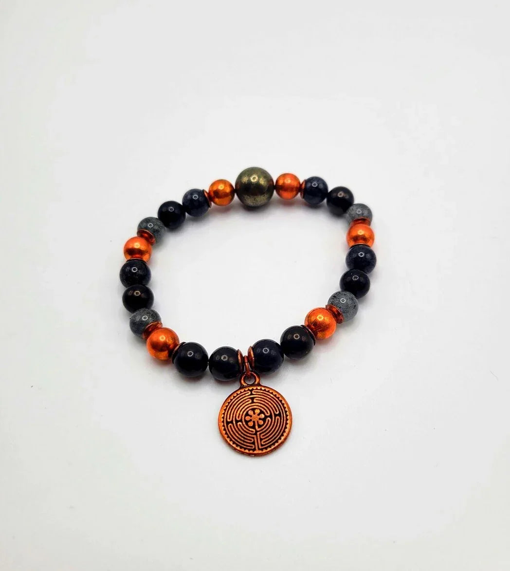 Spiritual beaded bracelet with black, orange, gray beads and a round bronze labyrinth charm