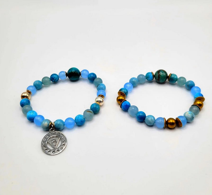 Blue beaded bracelets with gold accents and spiritual charm on white background