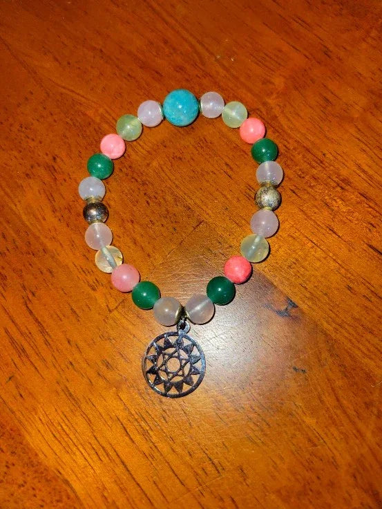 Colorful beaded spiritual bracelet with metal geometric charm on wooden surface