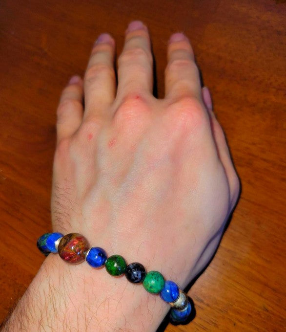 Hand wearing a multicolor beaded spiritual bracelet on wooden table