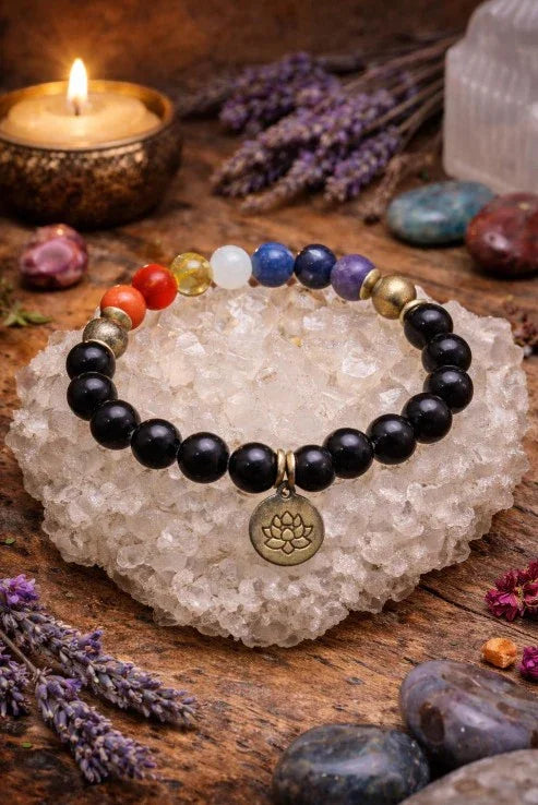 Chakra gemstone beaded bracelet with lotus charm on crystal, with candle and lavender in background