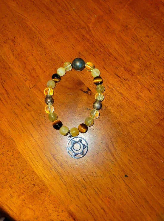 Beaded spiritual bracelet with multicolored stones and silver charm on wooden surface