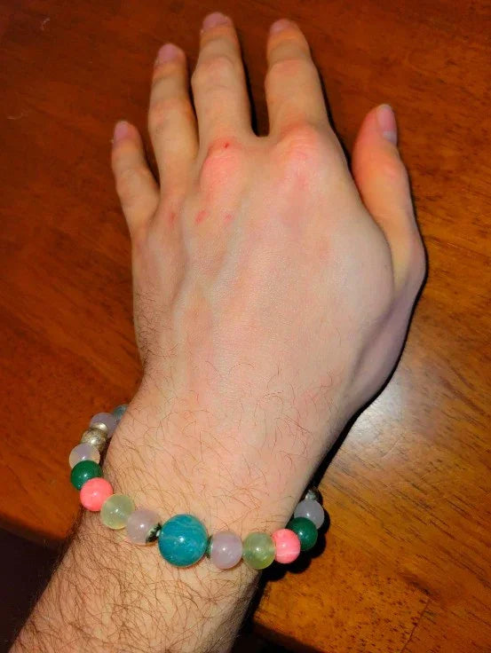 Hand wearing a colorful beaded spiritual bracelet on wooden table