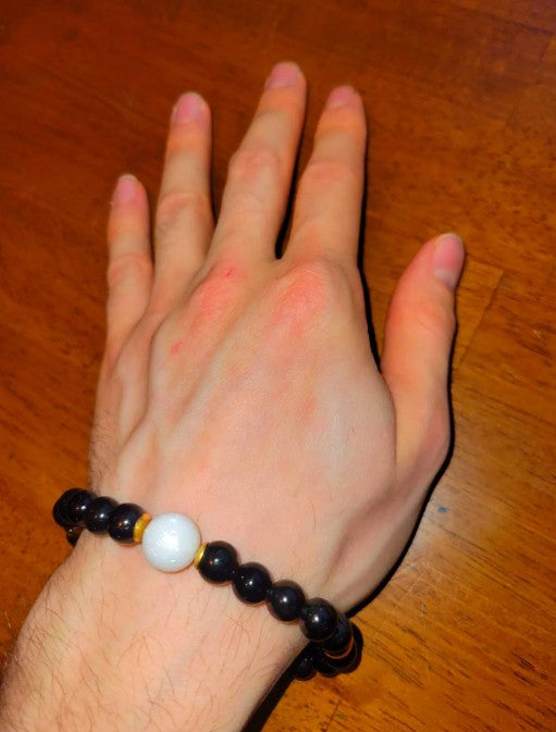 Black tourmaline and moonstone bracelet with silver accents, featuring spiritual healing and energy protection elements.