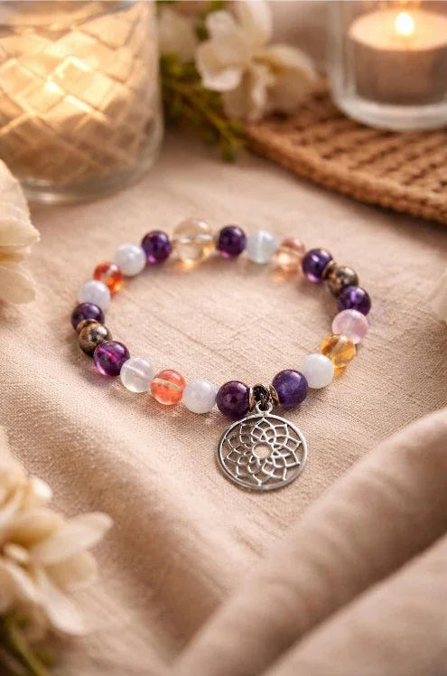 Colorful gemstone beaded spiritual bracelet with dreamcatcher charm on linen, candles nearby