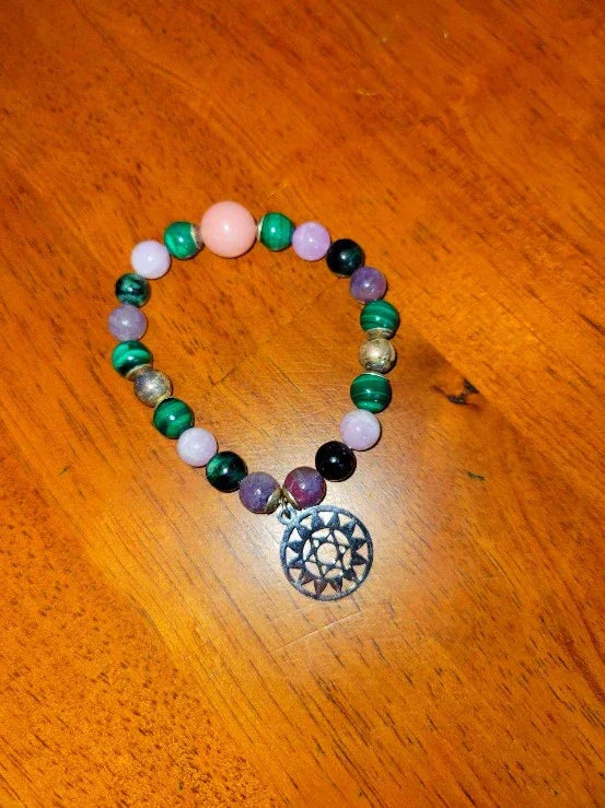Colorful gemstone beaded bracelet with spiritual mandala charm on wooden surface