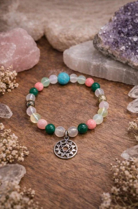 Colorful gemstone beaded bracelet with silver charm on wooden surface, surrounded by crystals.