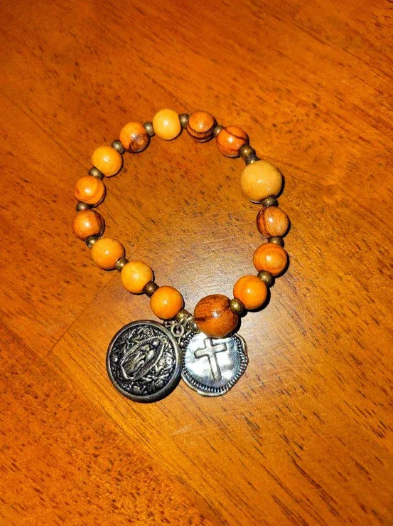 Wood bead spiritual bracelet with metal religious charms on a wooden surface