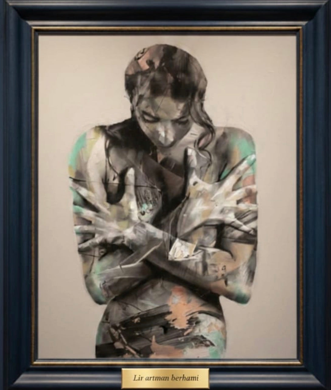 Framed abstract wall art of a woman with crossed arms, blending soft watercolor tones.